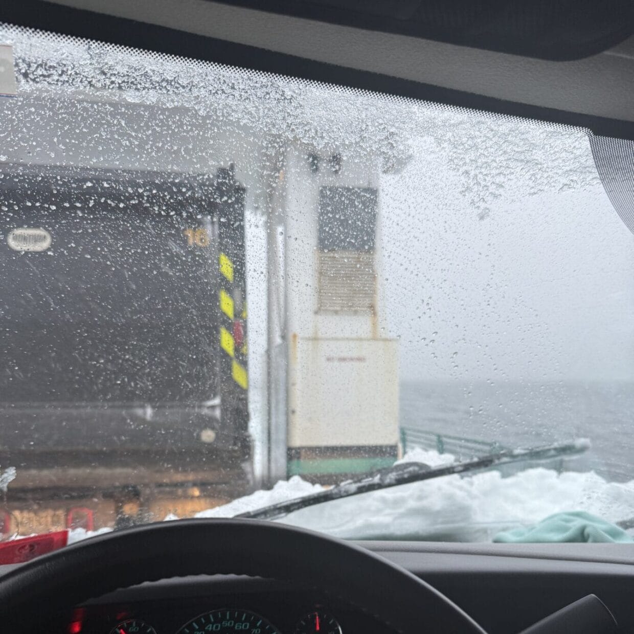 Two trucks on cargo ship in the ocean in winter.