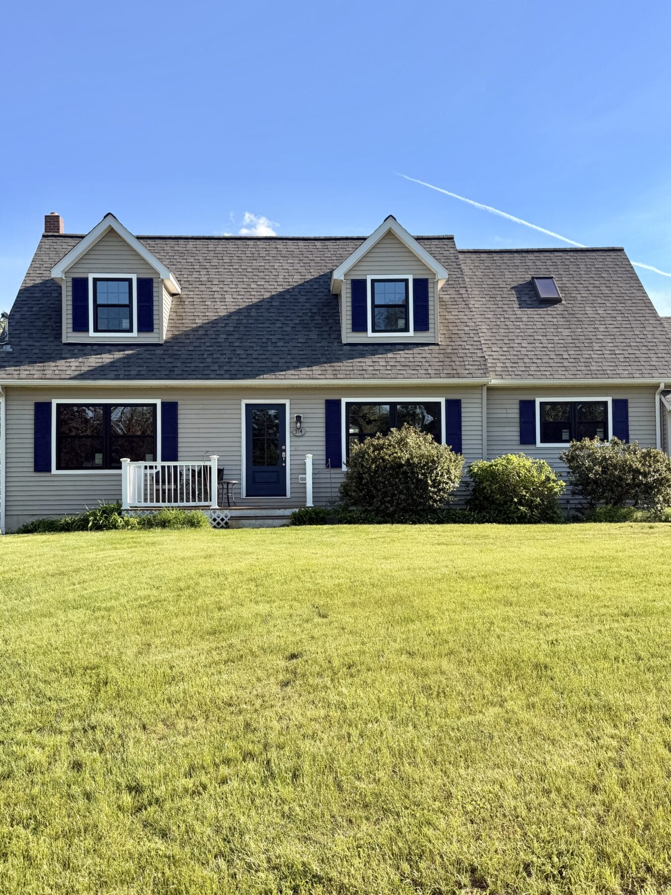 Modern farmhouse home exterior featuring black ProVia Endure replacement windows with colonial grids and white trim in Dover, New Hampshire