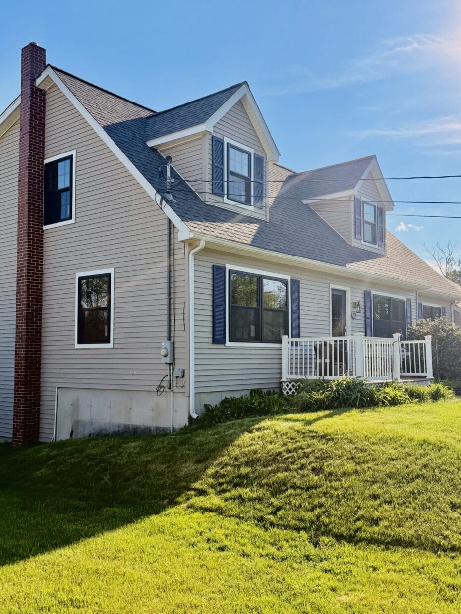 Side view of Dover, New Hampshire home featuring black ProVia Endure replacement windows with white trim and colonial grid patterns installed by Best Choice Windows & Doors